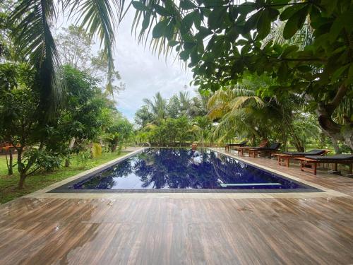 a swimming pool in a park with benches and trees at Hidden Garden Tangalle in Tangalle