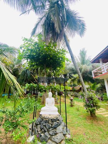 a statue sitting on a pile of rocks in a garden at Hidden Garden Tangalle in Tangalle