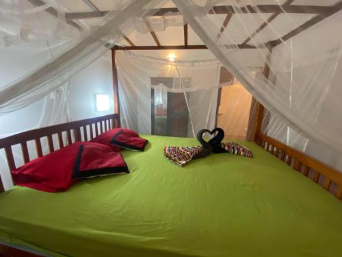 a bedroom with a green bed with a black object on it at Hidden Garden Tangalle in Tangalle