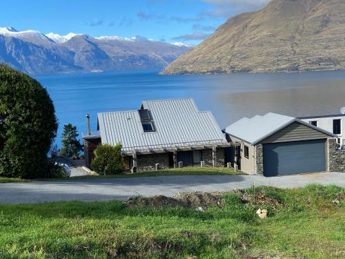 a house with a lake and mountains in the background at Queenstown Lake Panorama in Queenstown