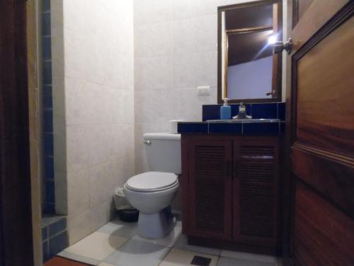 a bathroom with a toilet and a sink and a mirror at Hostal Cumbres de El Salvador in San Salvador