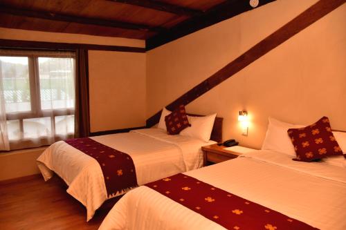 a hotel room with two beds and a window at Hotel Junvay in San Cristóbal de Las Casas