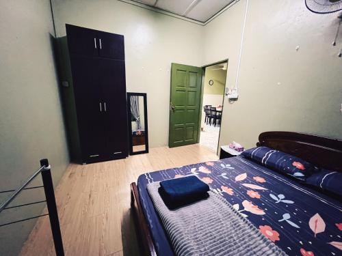 a bedroom with a bed and a green door at Arni Homestay - Geliga in Cukai
