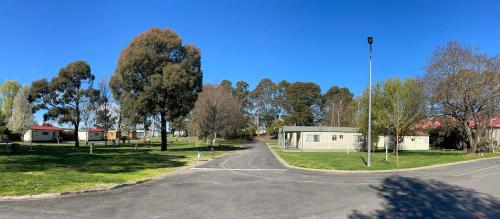 an empty street in a park with trees and a building at Jenolan Holiday Park Oberon in Oberon