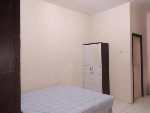 um quarto branco com uma cama e um armário em Penginapan al fatih em Kampungdurian