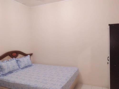 um pequeno quarto com uma cama com almofadas azuis em Penginapan al fatih em Kampungdurian