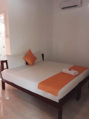 a bed with orange and white pillows in a room at Villa DeLorenta in Anuradhapura
