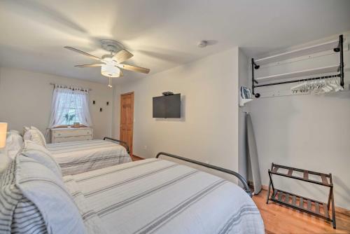 two beds in a room with a ceiling fan at Lake Luzerne Home with Fire Pit on Hudson River in Lake Luzerne