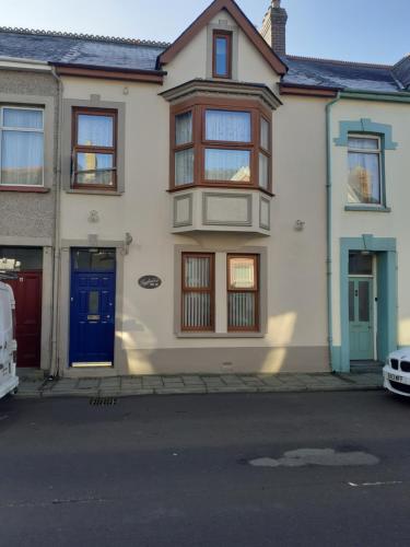 a white house with a blue door on a street at Vergam Terrace in Fishguard