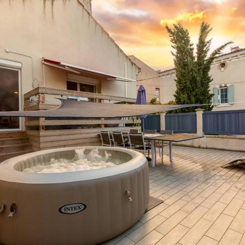 a hot tub on a patio with a table and a surfboard at Appartement Domloc in Carcassonne