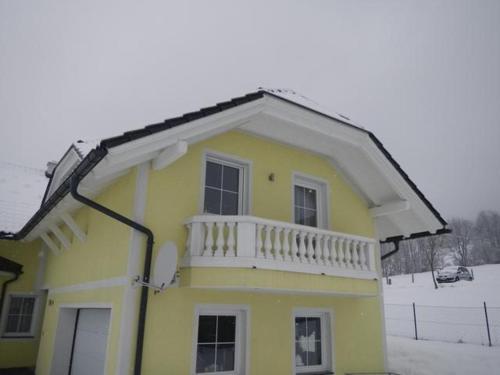 a yellow house with a balcony on top of it at Ferienwohnung Schmid in Sankt Martin am Grimming