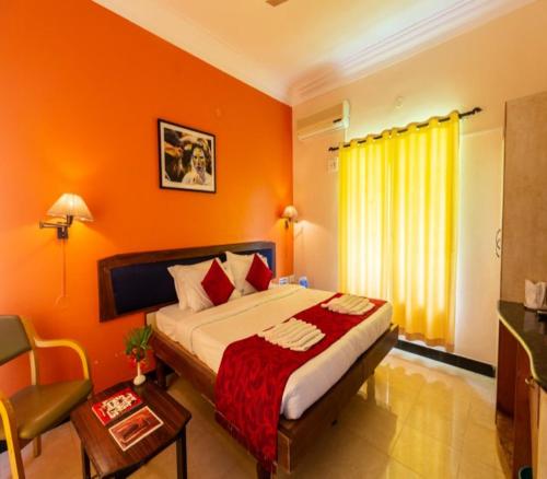 a bedroom with a bed with an orange wall at KSTDC Hotel Mayura Bhuvaneshwari Kamalapur in Hampi