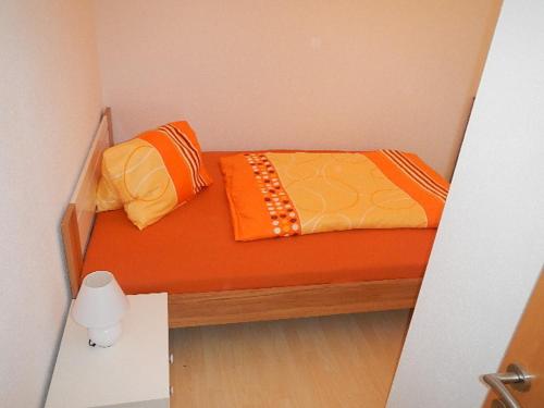 a small bedroom with an orange bed and two pillows at Ferienwohnung Schmid in Sankt Martin am Grimming