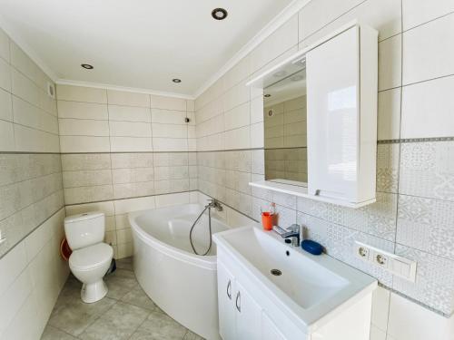 a bathroom with a tub and a toilet and a sink at Садиба Гармонія in Guta