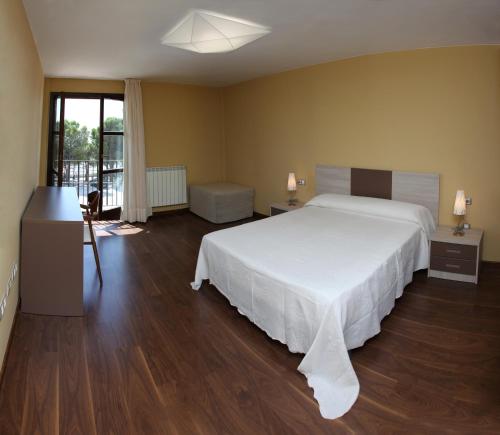 Hotel Santuario de Sancho Abarca في Tauste: غرفة نوم بسرير ابيض كبير وارضيات خشبية