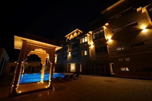 a building with a swimming pool at night at Sahdev Bagh in Pushkar