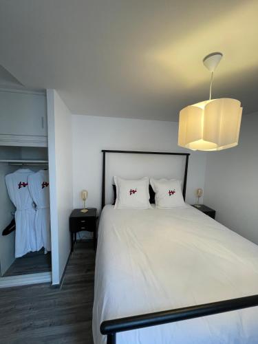 - une chambre avec un lit blanc et un lustre dans l'établissement Love Viou, à Ramonchamp