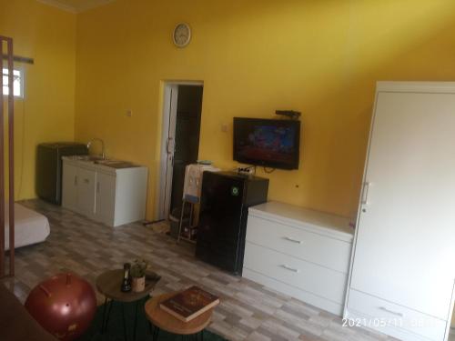 a living room with a tv on a yellow wall at Pondok Wammy Syariah in Cigasong