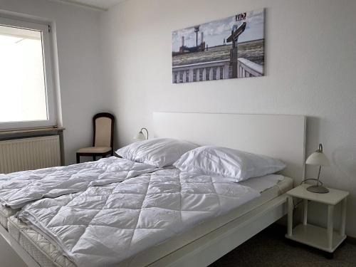 uma cama branca num quarto com uma fotografia na parede em Haus Atlantic Whg. 601 em Cuxhaven