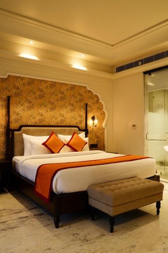 a bedroom with a large bed with orange and white pillows at Sahdev Bagh in Pushkar