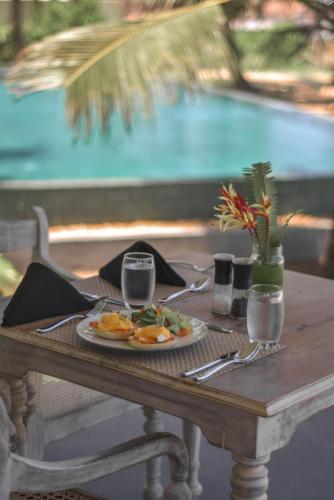 a wooden table with a plate of food on it at Naomi Beach Resort - Adults only in Weligama