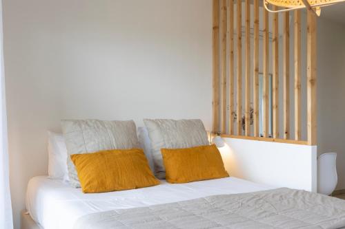 a white bed with two orange pillows on it at Casa Marina Cargèse in Cargèse
