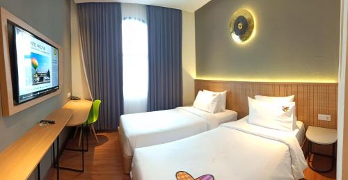 a hotel room with two beds and a flat screen tv at MaxOneHotels Loji Kridanggo @Boyolali in Boyolali