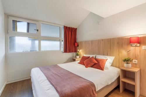 sypialnia z dużym białym łóżkiem z pomarańczowymi poduszkami w obiekcie Dunewave - spacious house for 8 persons in Westende w mieście Middelkerke