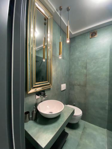 a bathroom with a sink and a toilet and a mirror at Apartments Lux in city center Lviv in Lviv