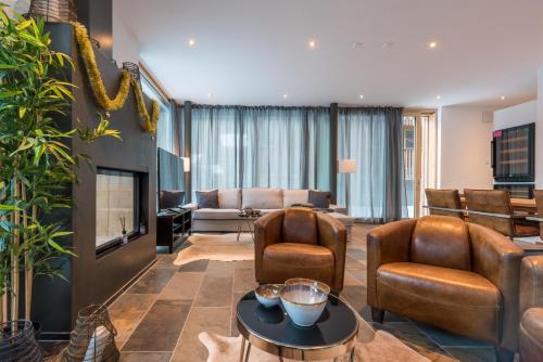 ein Wohnzimmer mit Ledersesseln und einem TV in der Unterkunft Montela Hotel & Resort - Montela Pavillon in Saas-Grund