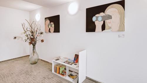 a white room with a vase and paintings on the wall at Boutique-Hotel Kronenstuben in Ludwigsburg