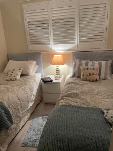 una camera con 2 letti e una lampada su un comodino di Ocean's Edge a Perranporth