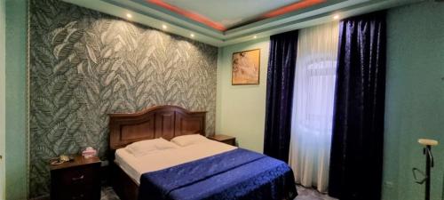 een slaapkamer met een bed met een blauw dekbed bij Ureni Hotel in Kʼasakh