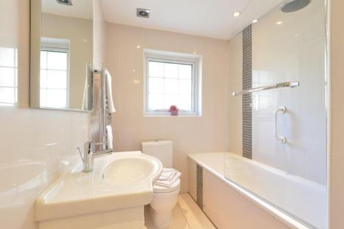 a bathroom with a sink and a tub and a toilet at Rosemorran Holiday Apartments in St Ives