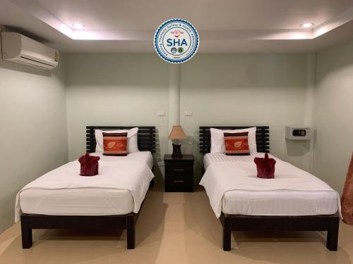 two beds in a room with a sign on the wall at Naiyang Seaview Place Resort in Nai Yang Beach