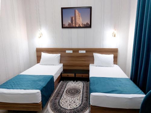 a room with two beds and a picture on the wall at Garden Plaza Bukhara in Bukhara