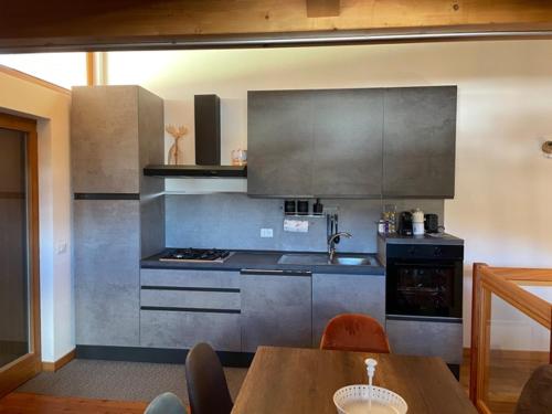 a kitchen with stainless steel appliances and a wooden table at Mansarda Eghel in Lavarone