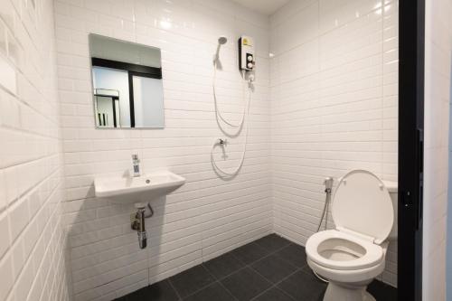 a white bathroom with a toilet and a sink at WiRE BANGKOK PRAKHANONG in Amphoe Phra Khanong