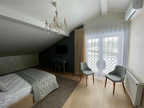 sypialnia z łóżkiem, 2 krzesłami i oknem w obiekcie Sadyba Lisova w mieście Tarnopol