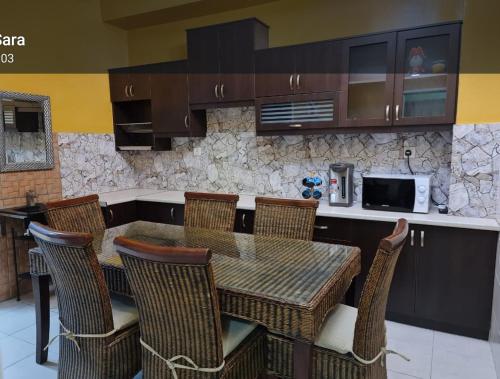 eine Küche mit einem Tisch, Stühlen und einer Mikrowelle in der Unterkunft Villa Suria SemiD Homestay Shah Alam in Shah Alam