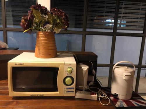 a microwave with a vase on top of it at Bluefin Guesthouse in Bangkok