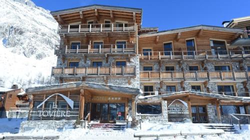 a large wooden building with snow in front of it at Hotel La Toviere in Val dʼIsère