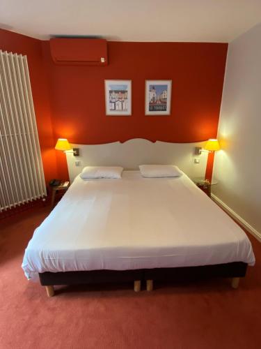 a bedroom with a large white bed with orange walls at Hôtel De Wimereux in Wimereux