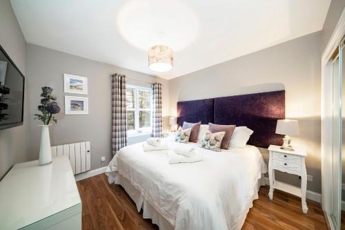 ein Schlafzimmer mit einem großen weißen Bett und einem Fenster in der Unterkunft The Pines - Stunning 3 Bedroomed Apartment, Gleneagles in Auchterarder
