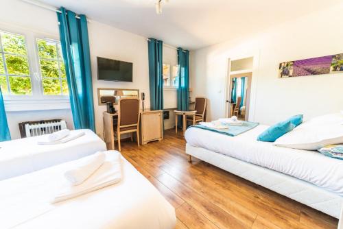 - 2 lits dans une chambre dotée de rideaux bleus dans l'établissement Logis Hôtels La Bastide des Golfs, à Mouans-Sartoux