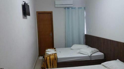 - une petite chambre avec 2 lits et un miroir dans l'établissement Hotel Jerusalém 2, à Goiânia