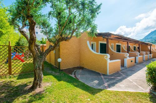 a yellow house with a tree and a fence at Hotel Parco Delle Agavi in Ischia