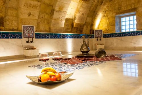 a bowl of fruit on a table with two glasses of wine at Kayakapi Premium Caves Cappadocia in Urgup