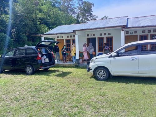 two cars parked in a yard in front of a house at Rago's Homestay in Kelimutu