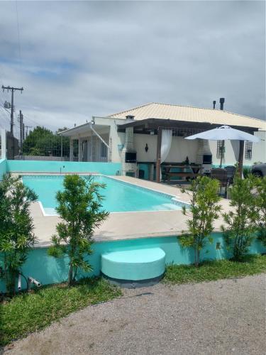una piscina azul frente a una casa en 02 - CASA praia PINHEIRA pousada, en Palhoça